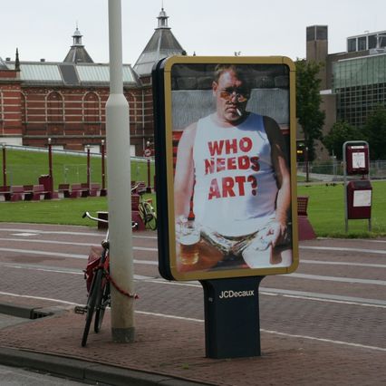 panneau sucette JCDecaux avec un homme gros qui arbore un tee shirt Who needs art?, bière et clope